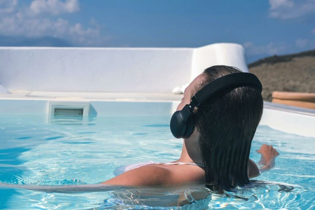 A_woman_listening_to_Bluetooth_headphones_far_from_her_audio_device-1100x733.jpg
